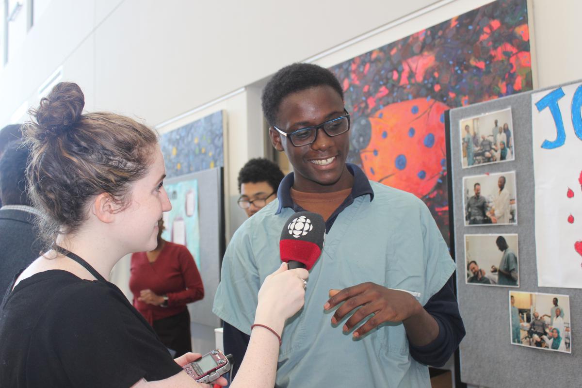 Rayan Primus de l’école secondaire John Paul discute de son projet sur les blessures avec une journaliste de la CBC.