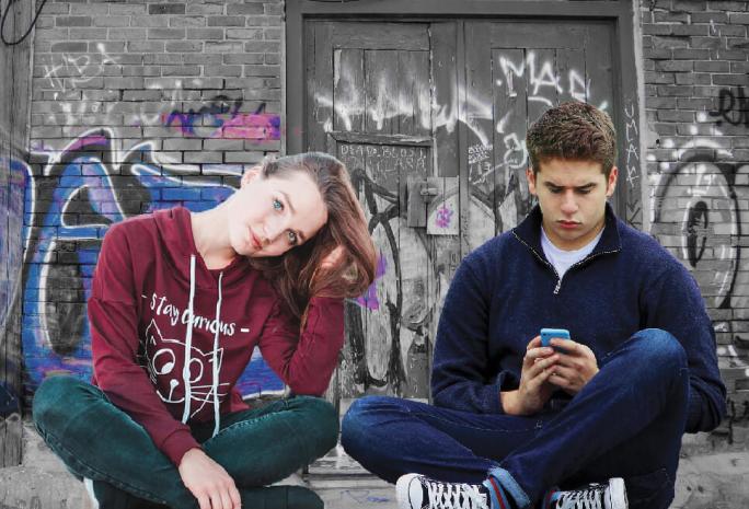 A young woman and a young man sit on the street edge.